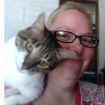 A tabby and white cat sits on my shoulder with her face pushed into mine