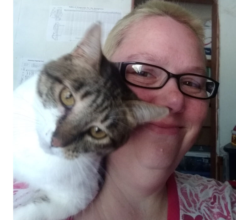 A tabby and white cat sits on my shoulder with her face pushed into mine