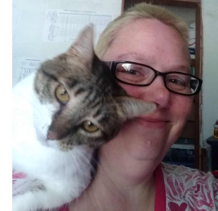 A tabby and white cat sits on my shoulder with her face pushed into mine